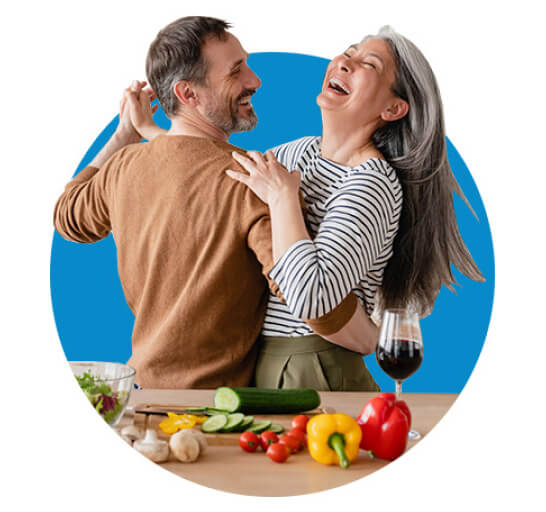 Energetic couple in their 50s dancing in the kitchen